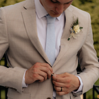 Groom in a knitted blue tie buttoning his suit