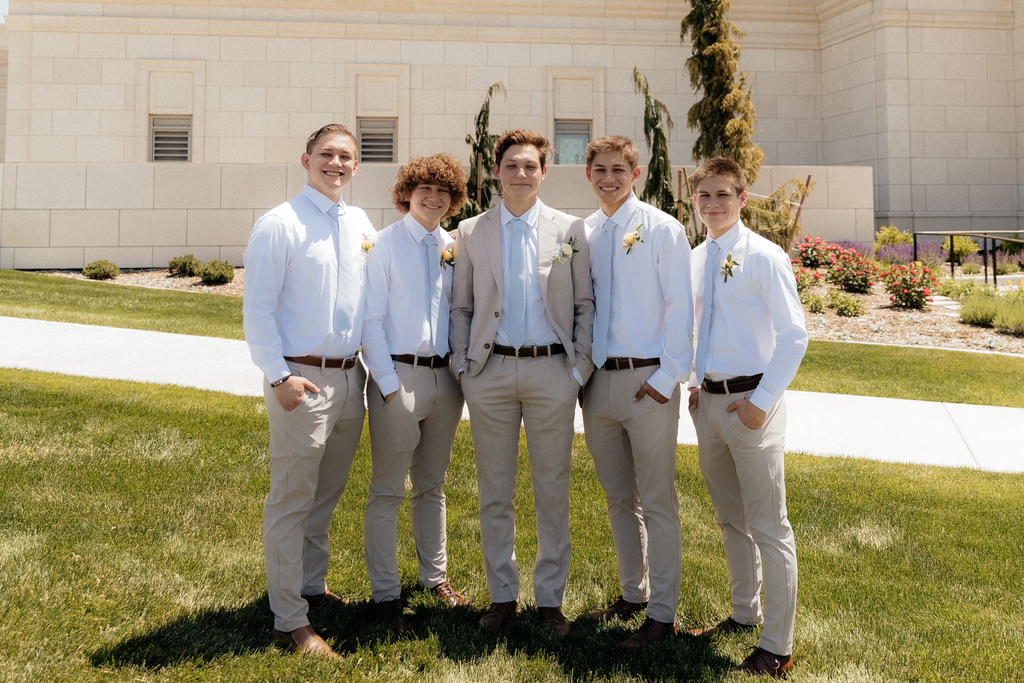 Group of men in knitted blue ties standing in front of a large building with a blue sky