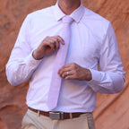 Man wearing a lavender colored necktie with red rocks in the background