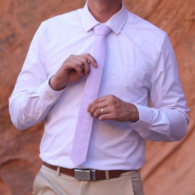Man wearing a lavender colored necktie with red rocks in the background
