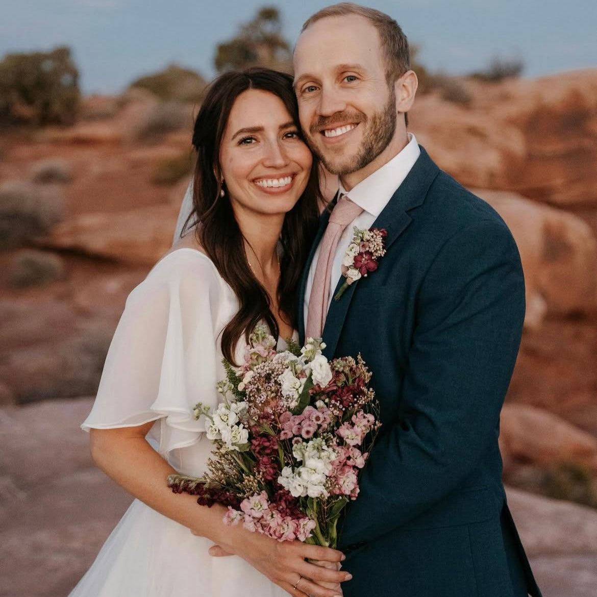 Couple in wedding attire standing together with a scenic background
