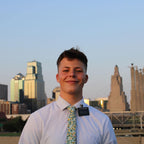 Missionary wearing a white shirt and floral tie with a city skyline in the background
